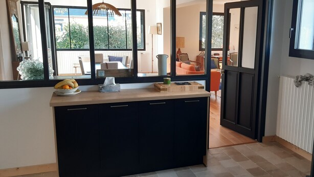 Een keuken met een centraal eiland, zwarte kastjes en uitzicht op het buitenbalkon.