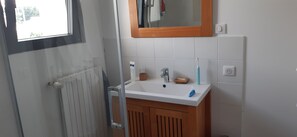 Ein Badezimmer mit einem weißen Waschbecken, einem Holzschrank und einem Spiegel darüber.