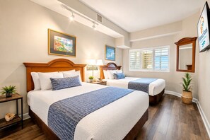 A hotel room with two beds, a large window, a painting, and a mirror.