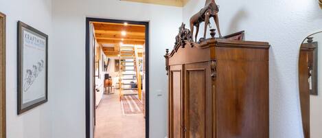 A hallway with a wooden cabinet, a framed picture, and a staircase leading to another room.