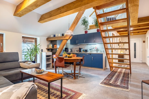 A modern living room with a sofa, dining table, and staircase.