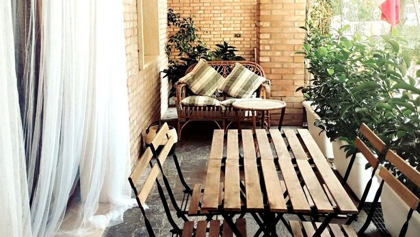 A patio with a wooden table and chairs, a wicker sofa, and a brick wall. - Charming 1-bedroom apartment with AC, WiFi in lovely Senigallia Bilocale (Senigallia)