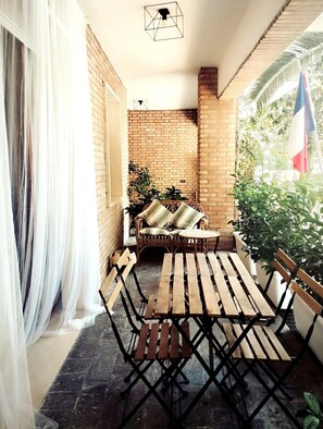 A patio with a wooden table and chairs, a wicker sofa, and a brick wall. - Charming 1-bedroom apartment with AC, WiFi in lovely Senigallia Bilocale (Senigallia)