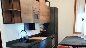 A modern kitchen with a built-in microwave, a sink, and a dining area with red chairs. - Charming 1-bedroom apartment with AC, WiFi in lovely Senigallia Bilocale (Senigallia)