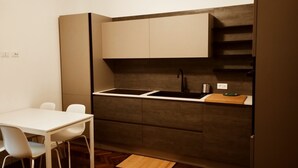 A compact kitchen with a white countertop, a black sink, and a wooden cutting board. There are two white chairs and a small rug on the floor. - Charming 1-bedroom apartment with AC, WiFi in lovely Senigallia Bilocale (Senigallia)