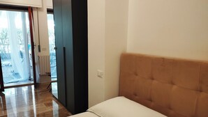 A bedroom with a bed, a wooden floor, a door, and a view of the outside. - Charming 1-bedroom apartment with AC, WiFi in lovely Senigallia Bilocale (Senigallia)