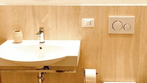 A bathroom with a round mirror, a sink, a toilet, and a towel dispenser. - Charming 1-bedroom apartment with AC, WiFi in lovely Senigallia Bilocale (Senigallia)