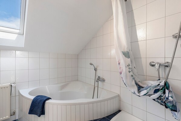 Une salle de bain avec une baignoire, une douche et une fenêtre.
