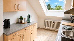 A modern kitchen with wooden cabinets, a coffee maker, a plant, and a skylight. - Casa di Napolitano at Lake Constance – Modern Attic Apartment Near the Lake (Radolfzell am Bodensee)