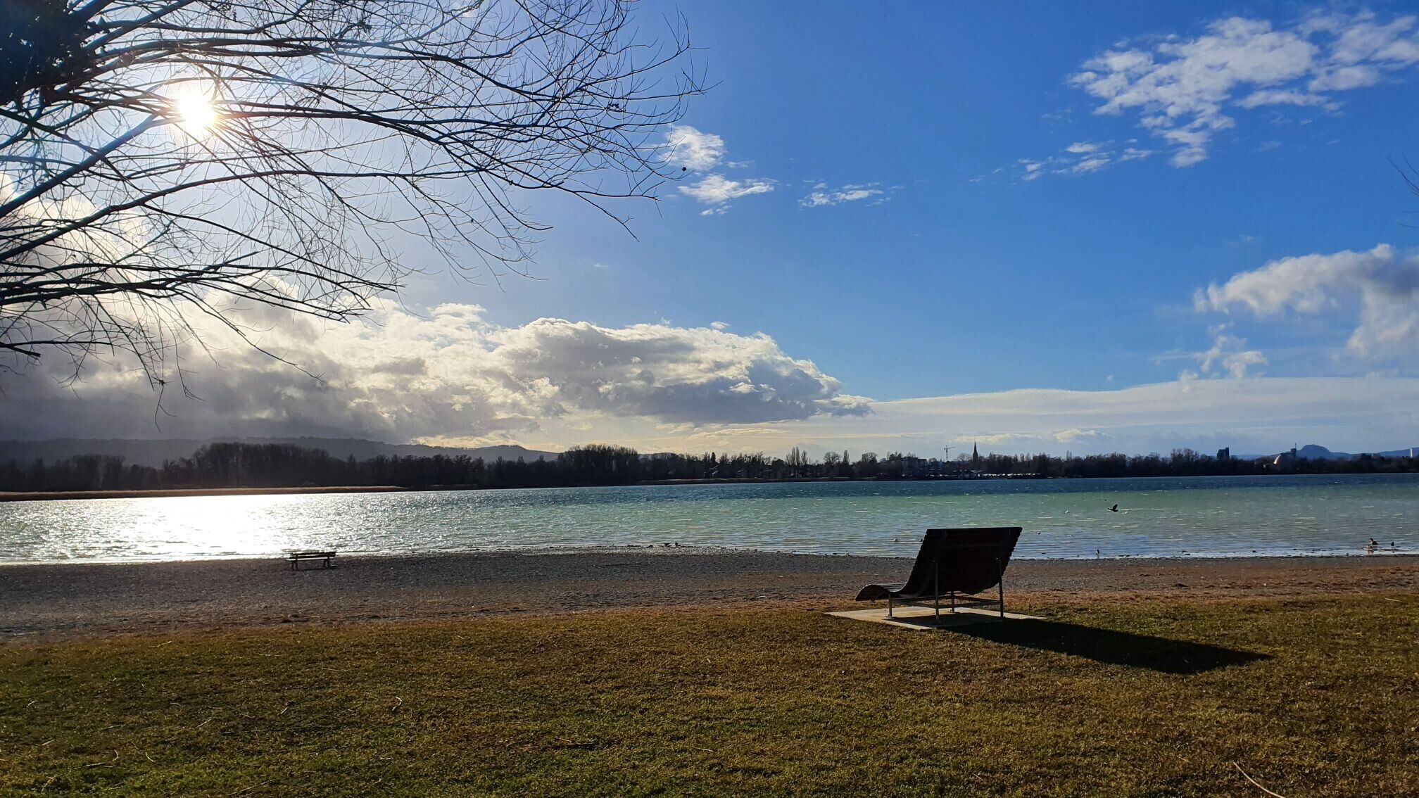Une vue sur le lac, avec un banc et un ciel dégagé.