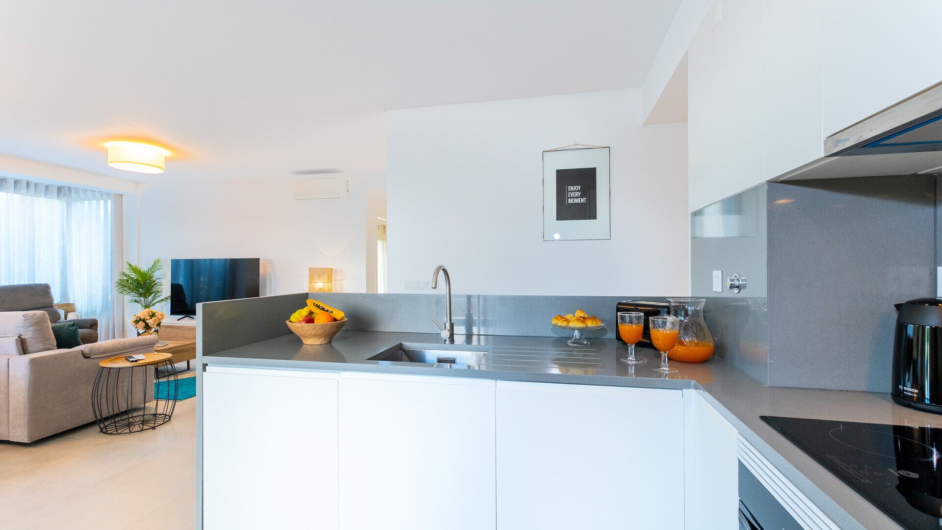 Una cucina moderna con isola centrale, lavello integrato e una macchina da caffè Bosch.