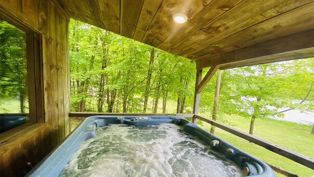 Un bain à remous dans un chalet en bois avec vue sur une forêt.