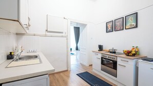 Ett modernt kök med vita skåp, en ugn i rostfritt stål och ett litet kylskåp.