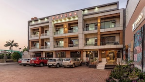A multi-story hotel with a prominent "BAJERA" sign, featuring a modern architectural design with balconies and a brick-paved entrance area. - Treebo Basera (Mathura)