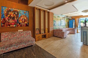 A hotel lobby with floral-patterned sofas, a large decorative painting, and a traditional statue.