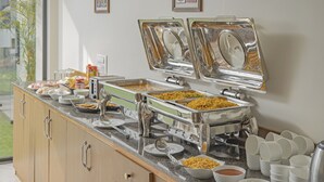 A buffet setup with various dishes and utensils. - Treebo Basera (Mathura)