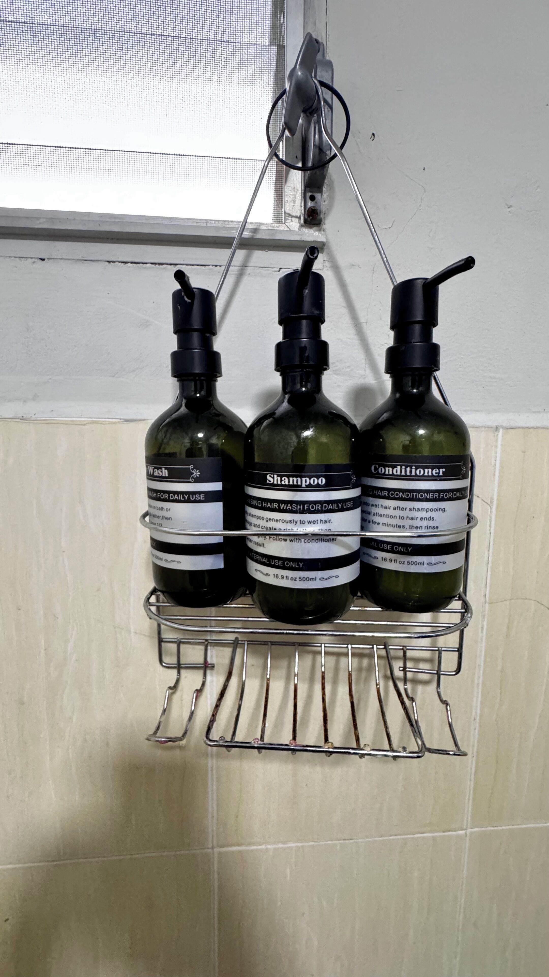 Three bottles of hair care products on a metal rack against a wall.