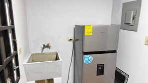 A compact kitchen with a stainless steel refrigerator, a sink, and a water dispenser. - Peace N' Green (David)