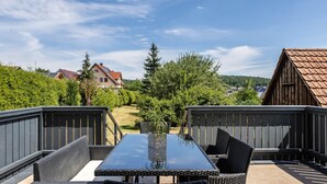 An outdoor patio with a table and chairs, surrounded by a wooden fence and greenery. - Holiday Home 'Ferienhaus Barockhaus Fulda' with Private Terrace, Private Garden and Wi-Fi (Petersberg)