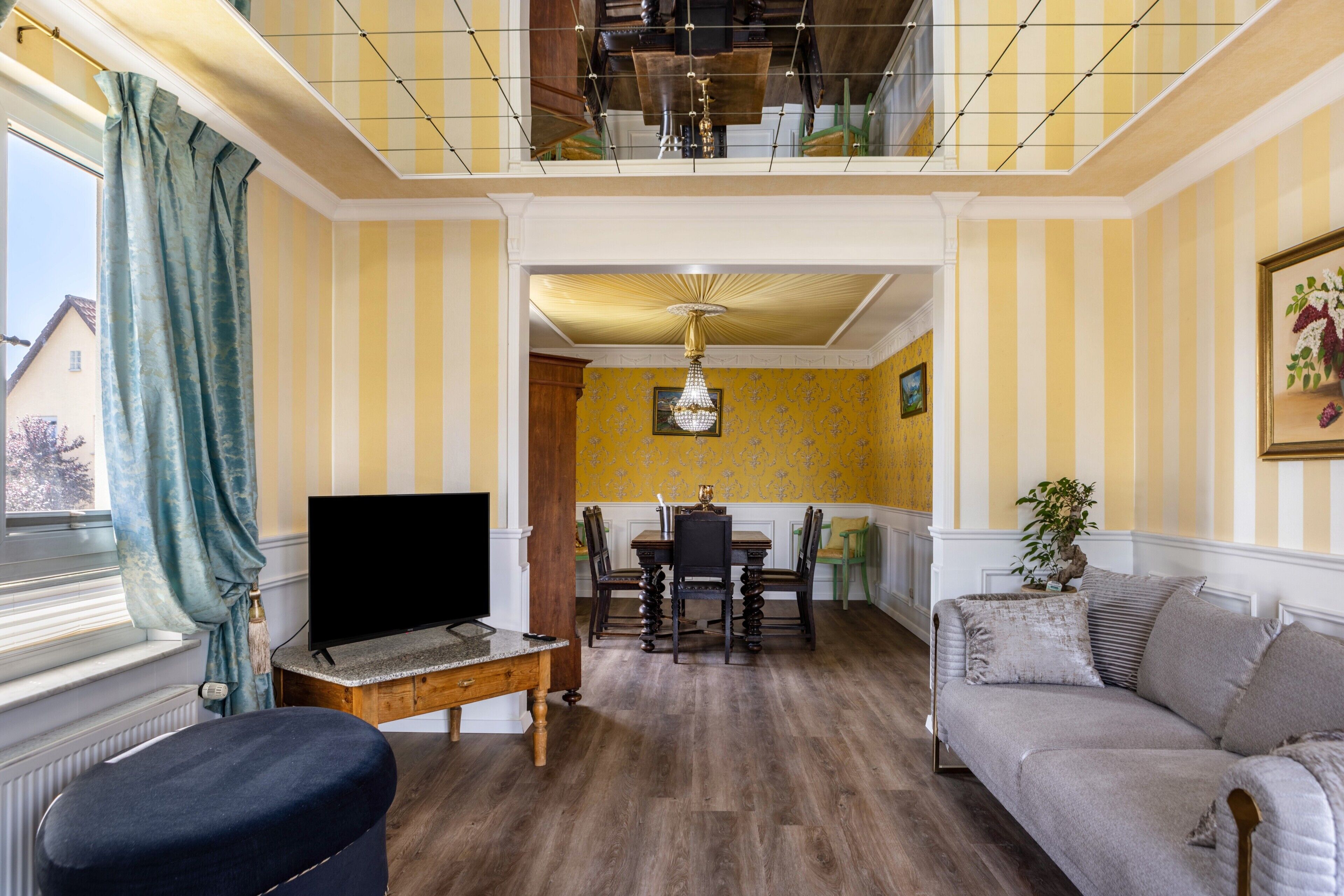 A living room with a TV, sofa, dining table, and chairs.