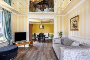 A living room with a TV, sofa, dining table, chairs, and a staircase. - Holiday Home 'Ferienhaus Barockhaus Fulda' with Private Terrace, Private Garden and Wi-Fi (Petersberg)
