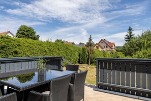 An outdoor patio with a table and chairs, surrounded by greenery and houses in the background. - Holiday Home 'Ferienhaus Barockhaus Fulda' with Private Terrace, Private Garden and Wi-Fi (Petersberg)