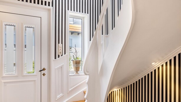 A staircase with white walls, a door with glass panels, and a window with a plant. - Holiday Home 'Ferienhaus Barockhaus Fulda' with Private Terrace, Private Garden and Wi-Fi (Petersberg)