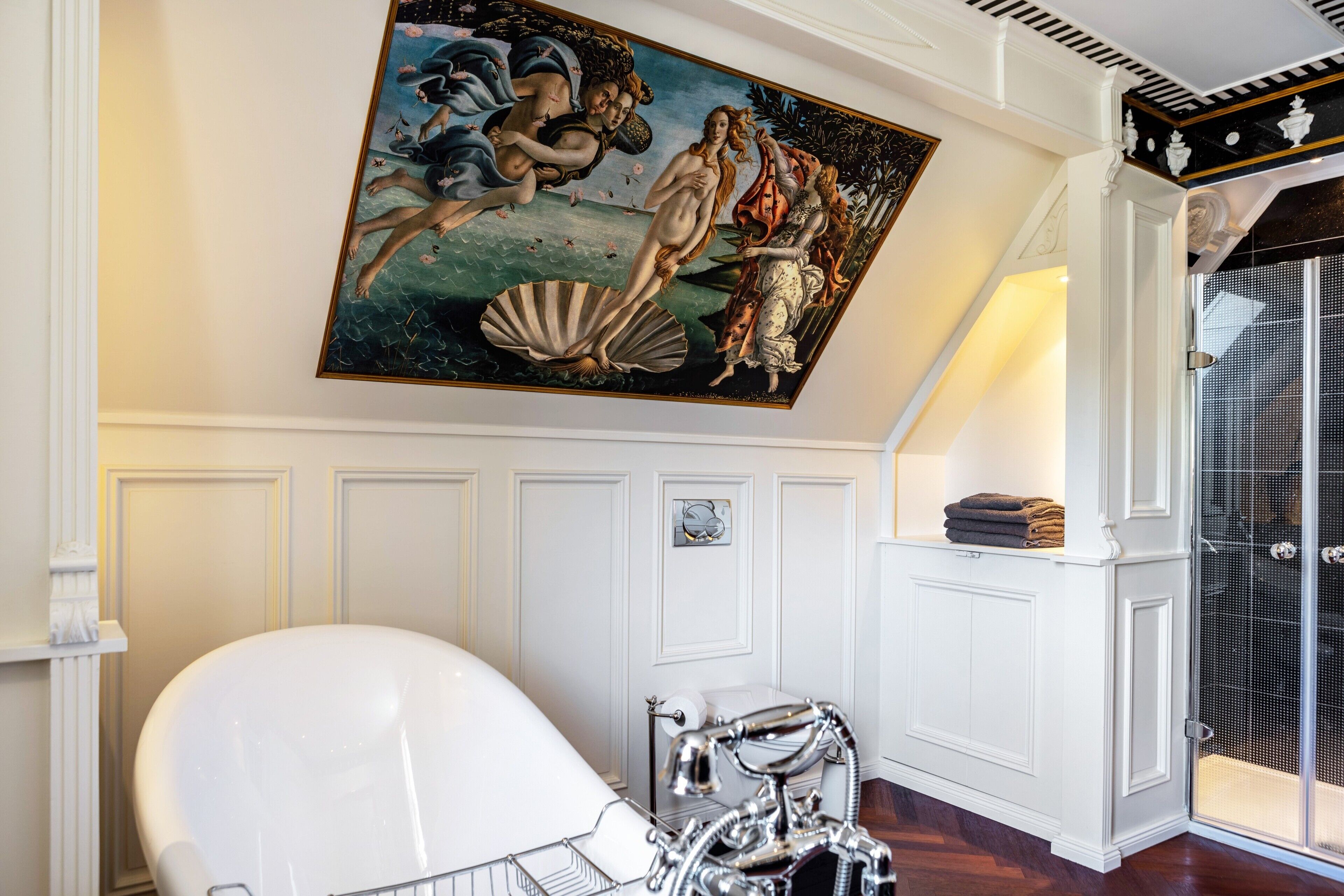 A bathroom with a white bathtub, a shower, and a wall-mounted painting.
