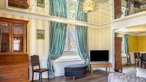 A room with a TV, wooden furniture, a window with curtains, and a chandelier. - Holiday Home 'Ferienhaus Barockhaus Fulda' with Private Terrace, Private Garden and Wi-Fi (Petersberg)