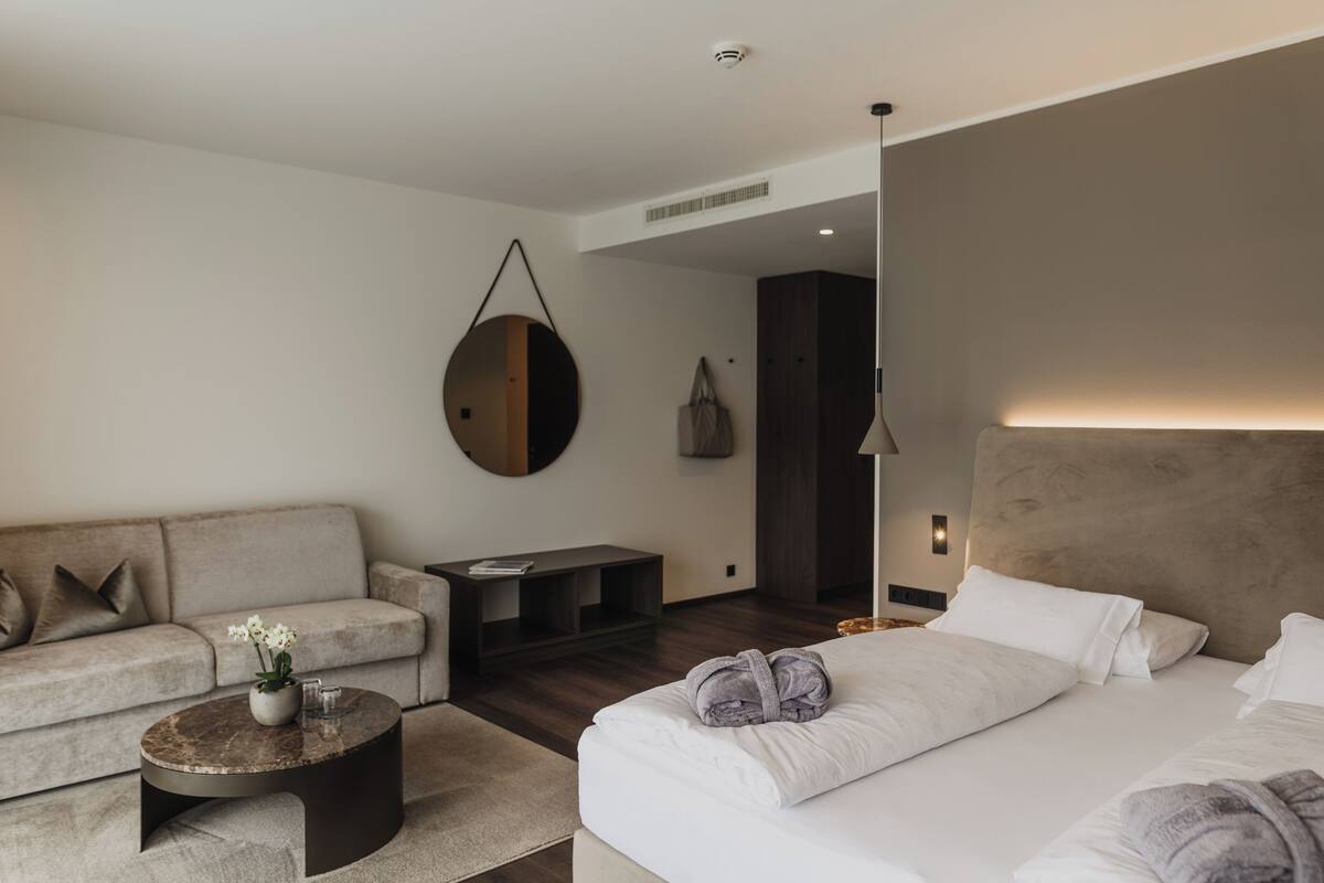 Une chambre d’hôtel moderne équipée d’un lit, d’un canapé, d’une table basse et d’un miroir.