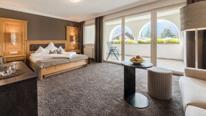 Habitación de hotel moderna con una cama grande, una mesita redonda y vistas al exterior a través de amplios ventanales.