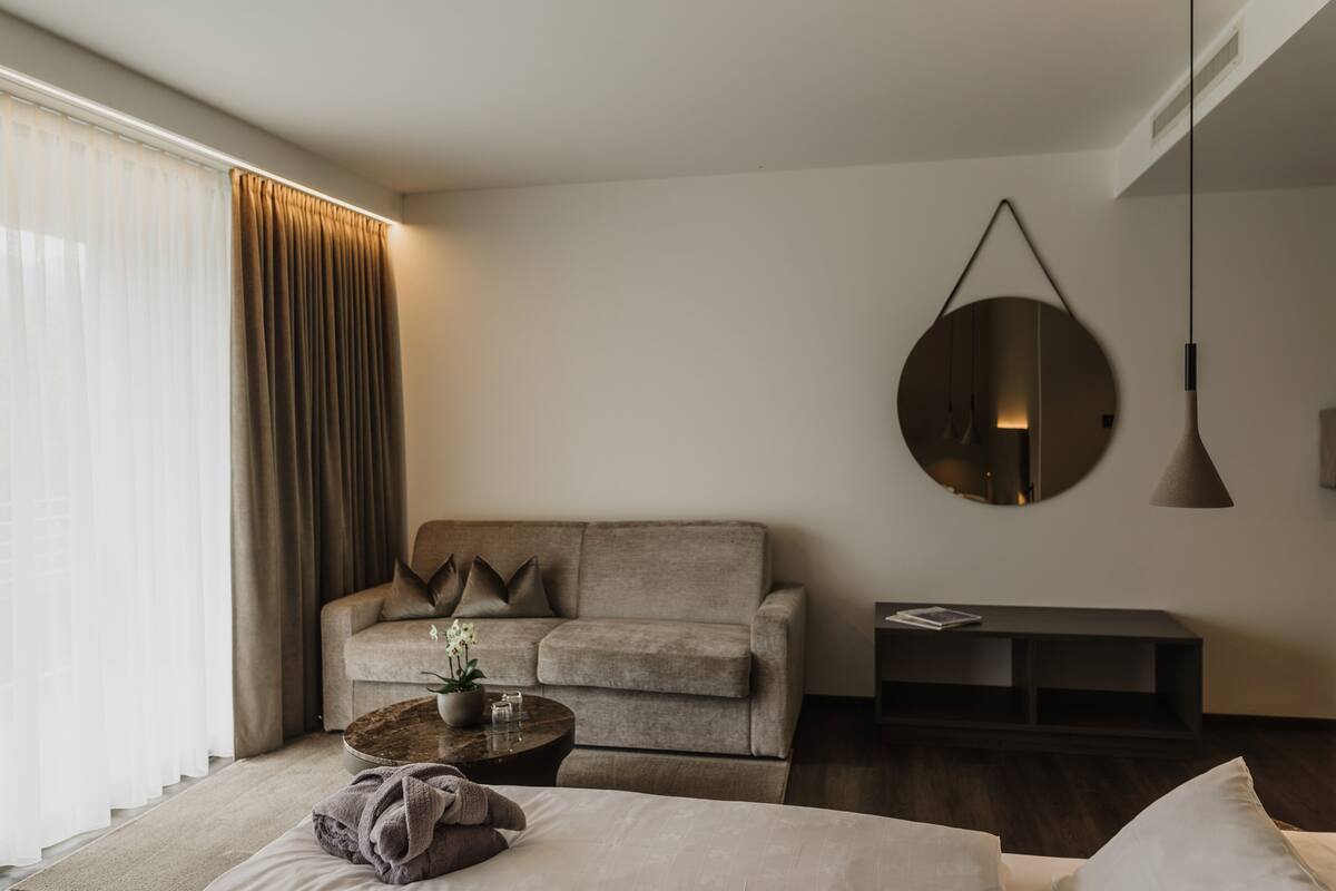 Un salon moderne avec un canapé, une table basse ronde et un miroir suspendu.
