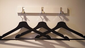 A wall-mounted rack with three black hangers and a white shelf above. - TAKETO STAY PREMIERE 201 (Sapporo)