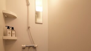 A small, white bathroom with a shower, a mirror, and two shelves with toiletries. - TAKETO STAY PREMIERE 201 (Sapporo)