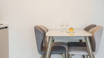A small dining table with two chairs, two wine glasses, and a dessert on a plate.