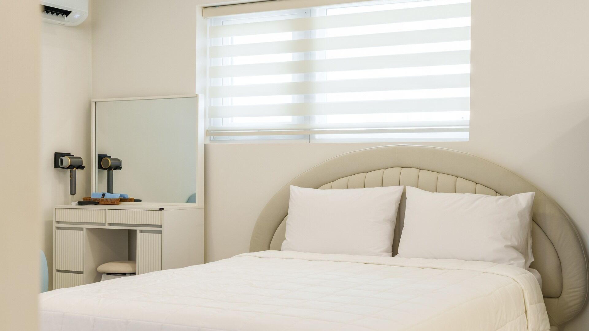 A bedroom with a bed, a dresser, a mirror, and a window with blinds.