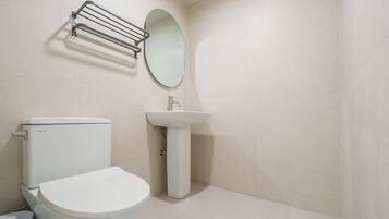 Un baño con inodoro, lavamanos sobre pedestal y barra para toallas.