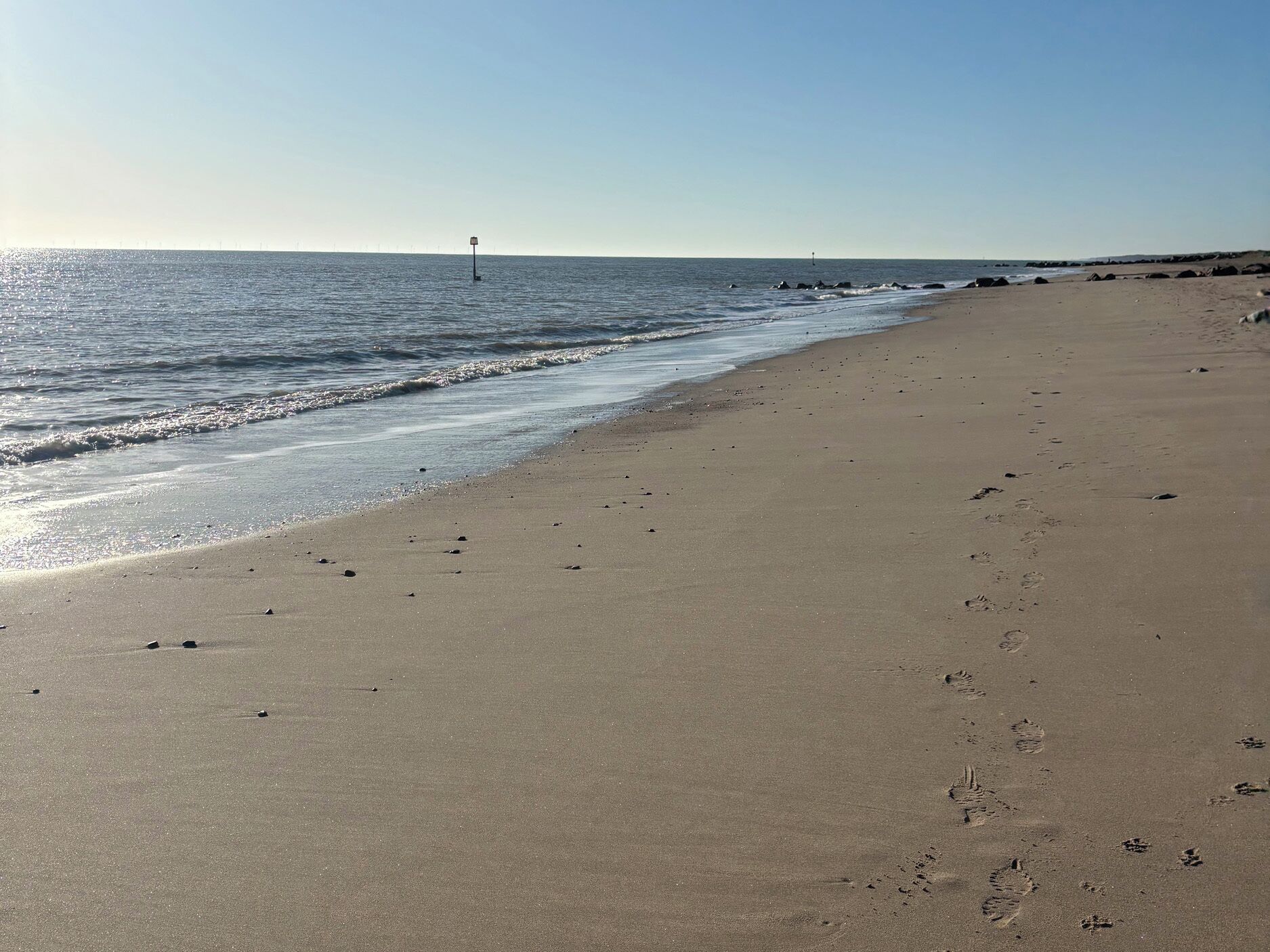 Une vaste plage de sable fin, avec des vagues douces et un ciel dégagé.