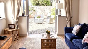 Una sala de estar con un sofá azul, una mesa de centro de madera y vistas a un patio exterior.