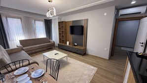 Een moderne woonkamer met een bank, een salontafel en een eethoek met borden en bestek.