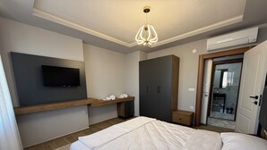 Een moderne slaapkamer met een bed, een aan de muur bevestigde televisie, een kledingkast en een airconditioner.