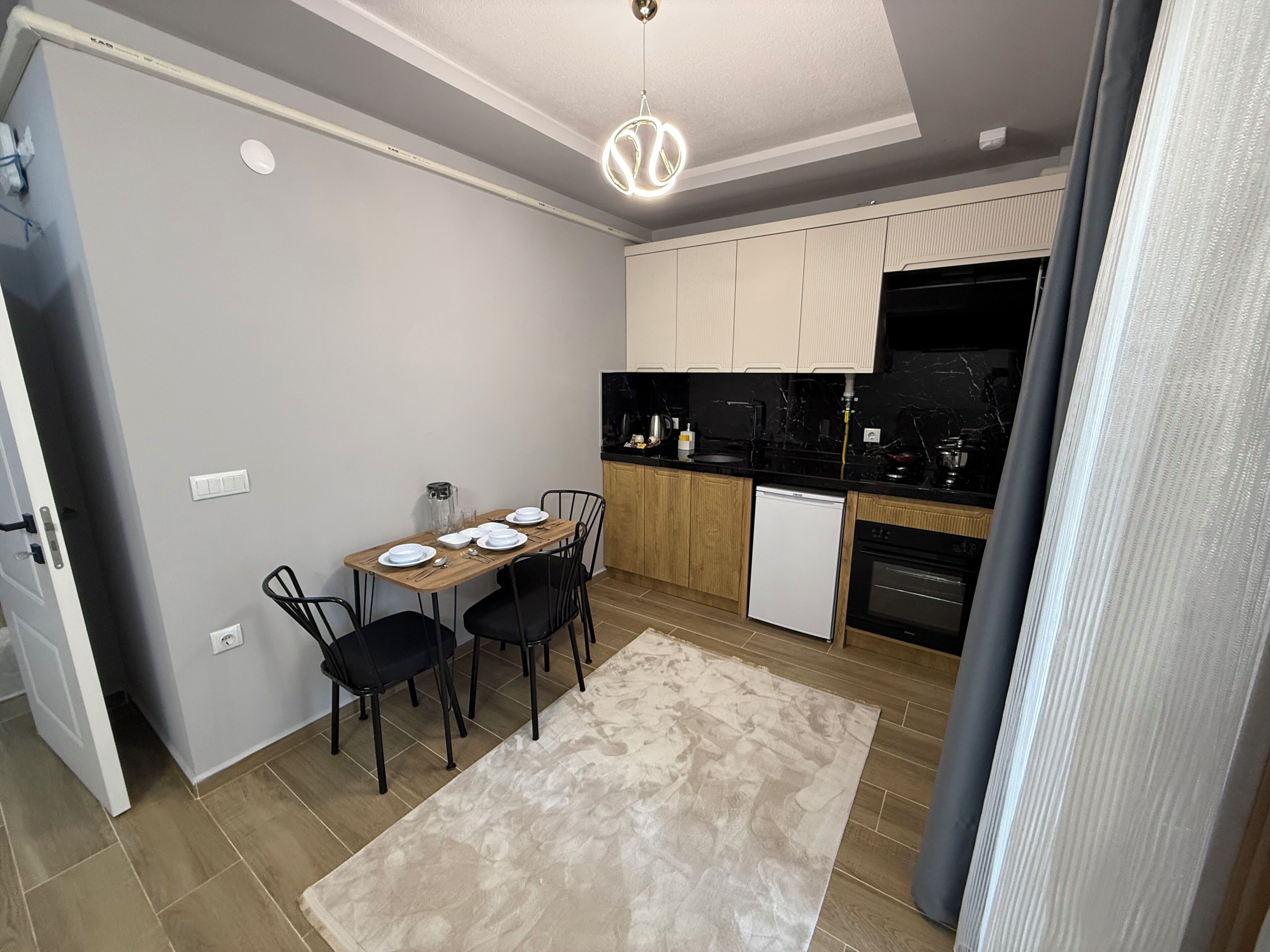 A compact kitchen with a dining area, featuring a small refrigerator, a microwave, and a sink.