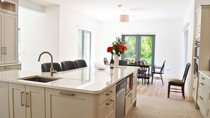 Una cocina moderna con una isla grande, armarios empotrados y una zona de comedor con mesa y sillas.