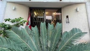 Une entrée d’immeuble avec une porte en verre, un drapeau et un portail de sécurité.