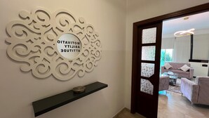 A modern interior with a decorative wall piece, a black shelf, and a glimpse of a living area with a sofa and a coffee table. - Kayan Hotel Apartments (Aley)