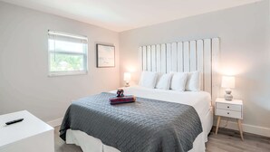 Une chambre à coucher avec un lit, des tables de chevet, une fenêtre et un tableau au mur.