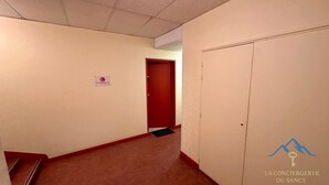 Un pasillo con piso alfombrado, una puerta roja y un cartel que indica prohibido fumar.