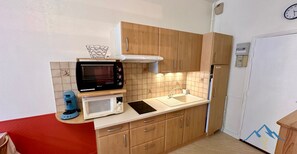Eine kleine Küche mit Holzausstattung, einer Mikrowelle, einer Kaffeemaschine und einem Kühlschrank.