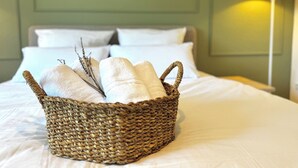 Een rieten mand met handdoeken op een bed in een kamer met een groene wand en een lamp.