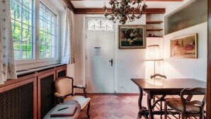 A dining area with a wooden table and chairs, a chandelier, and a window with curtains.